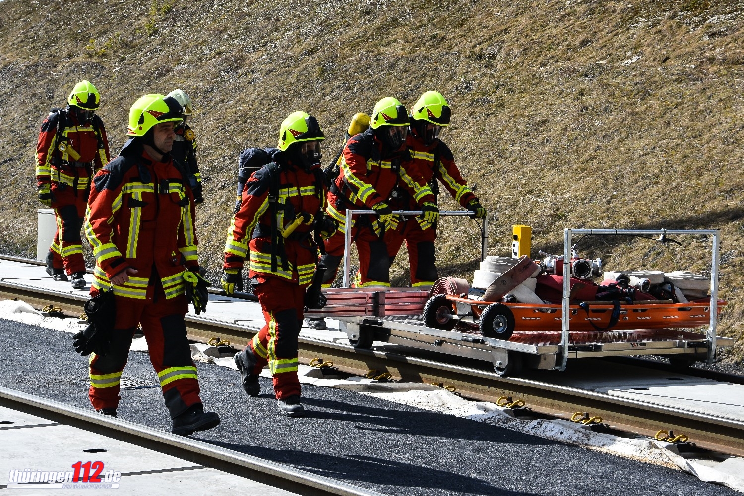 Ein Löschtrupp transportiert Schaluchmaterial über einen Schienenrollwagen zum Einsatzort